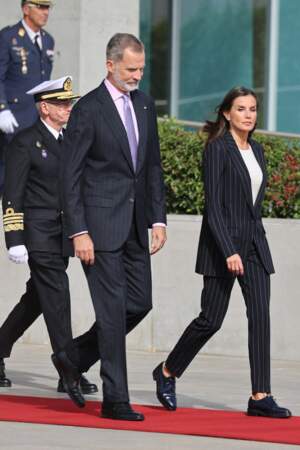 Le roi Felipe VI d'Espagne et la reine Letizia, portent tous les deux un costume deux pièces rayé blanc, au départ de Madrid pour une visite de trois jours en Allemagne le 16 octobre 2022