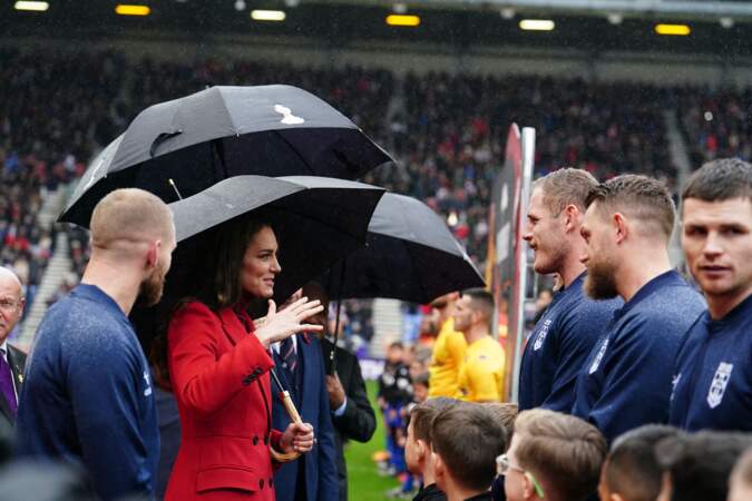 La princesse de Galles dans un manteau Alexander McQueen en discussion avec l'équipe d'Angleterre de rugby avant les 1/4 de finale de la Coupe du Monde de Rugby à XIII le 5 novembre 2022 à Wigan