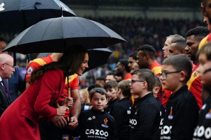 Kate Middleton dans un manteau Alexander McQueen discute avec les enfants avant le match "Angleterre vs Papouasie Nouvelle-Guinée" en 1/4 de finale de la Coupe du Monde de Rugby à XIII à Wiganle 5 novembre 2022 