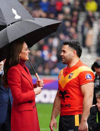 Kate Middleton dans un manteau rouge Alexander McQueen en discussion avec le capitaine de Papouasie Nouvelle-Guinée de rugby avant les 1/4 de finale de la Coupe du Monde de Rugby à XIII à Wigan le 5 novembre 2022
