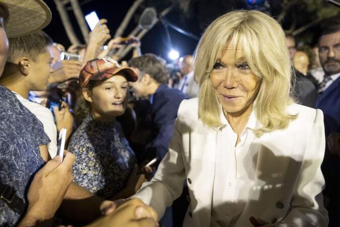 Bain de foule d'Emmanuel Macron et sa femme Brigitte vêtue d'une veste blanche associée à une chemise ton sur ton, après la commémoration du 78ème anniversaire de la libération de la ville de Bormes-les-Mimosas en août 2022