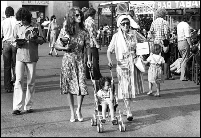 Charlotte Rampling naturelle en robe fleurie et ballerines à Saint Tropez en compagnie de son fils et de sa mère en 1977.