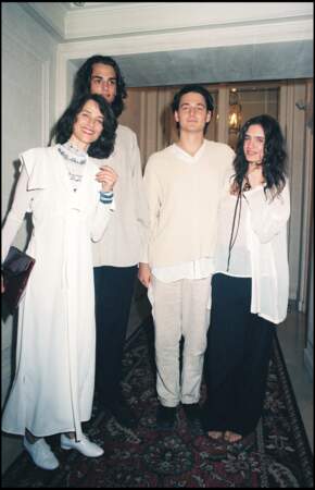 En robe façon caftan et sous pull bohème pour se rendre au défilé haute couture Versace avec ses enfants en 1995.