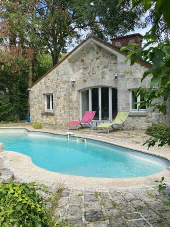 Une piscine avec pompe à chaleur et pool house avec douche et remise se trouve dans le jardin