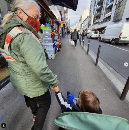 Josiane Balasko, masquée, tenant la main de son petit-fils Andy, dans les rues parisiennes.