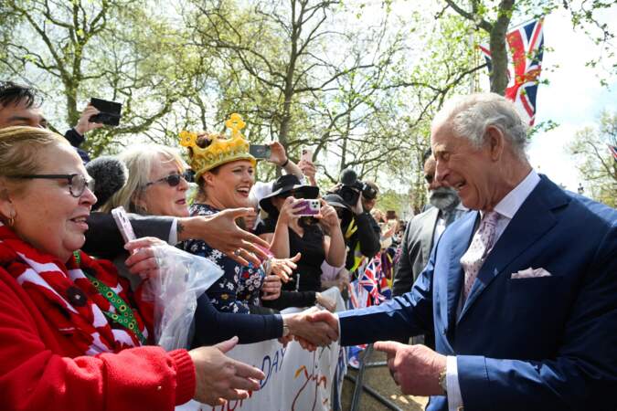 Charles III, le sourire aux lèvres, qui serre la main d'un sympathisant, devant le palais de Buckingham, à la veille de son couronnement, le 5 mai 2023.