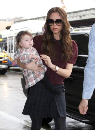 Harper Beckham, 7 mois, dans les bras de sa mère en petite robe chemise à carreaux.