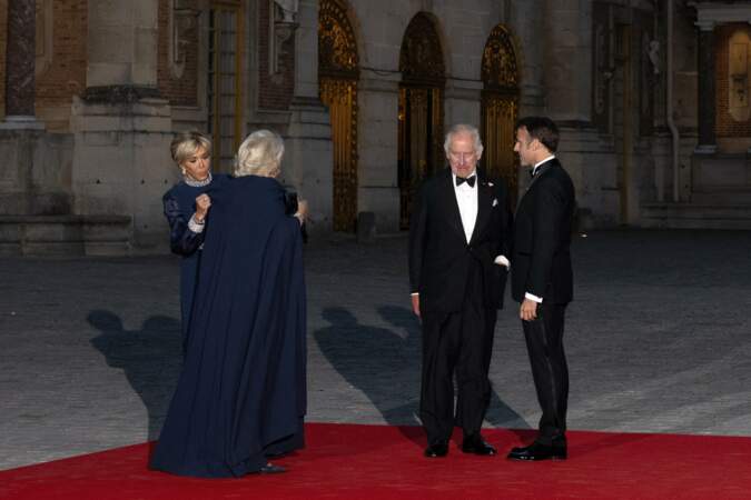 Brigitte Macron aide la reine Camilla avec la cape de sa robe, lors du dîner d'État au château de Versailles, ce mercredi 20 septembre 2023