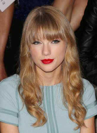 À la Fashion Week de Paris en octobre 2012, Taylors Swift assiste au defile Elie Saab avec ses cheveux légèrement ondulés et sa frange qui met en valeur son regard encadré de crayon. L'artiste dont la popularité ne cesse de croître fait également de la bouche rouge sa signature beauté. 