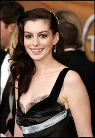 Anne Hathaway avec une coiffure side hair glamour, tombant en cascade sur son épaule droite
