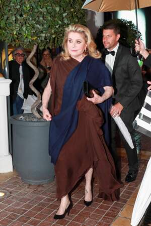 Catherine Deneuve quitte l'hôtel Majestic, dans une longue robe marron, lors du 76ᵉ Festival de Cannes, le 17 mai 2023