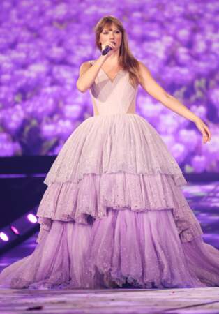 Taylor Swift en concert à Paris dans une robe à paillettes aux différentes teintes de violet avec un décolleté en V et une immense jupe à volants