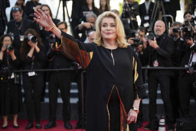 Catherine Deneuve confirme son statut d'icône de la mode dans un ensemble noir et or signé AMI sur le tapis rouge du Festival de Cannes, le 23 mai 2024