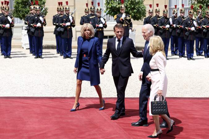 Emmanuel Macron tient la main de sa femme, alors qu'il guide Joe et Jill Biden vers l'Élysée, le 8 juin 2024.