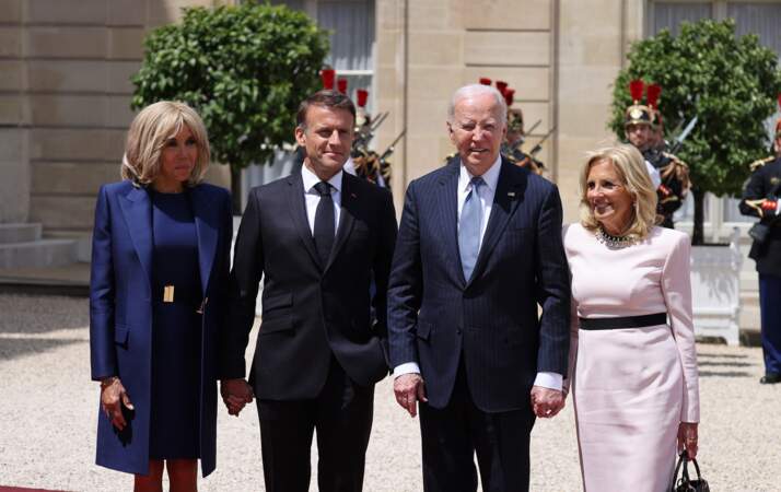 Brigitte et Emmanuelle Macron se tiennent la main au moment de poser avec le couple présidentiel américain, à l'Élysée, le 8 juin 2024.