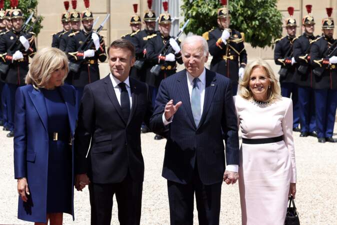 Joe Biden salue les photographes lorsqu'il pose avec Emmanuel et Brigitte Macron, à l'Élysée, le 8 juin 2024.
