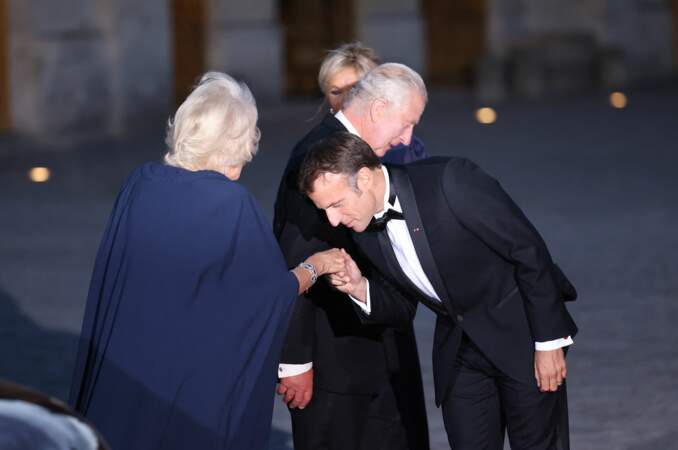 Le président de la République Emmanuel Macron salue d'un baise-main la reine Camilla, lors de son arrivée au dîner d'État, à Versailles, ce mercredi 20 septembre 2023